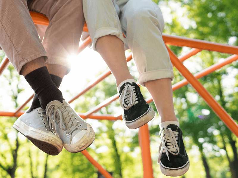 teenagers sat on a climbing frame with their smelly feet dangling down